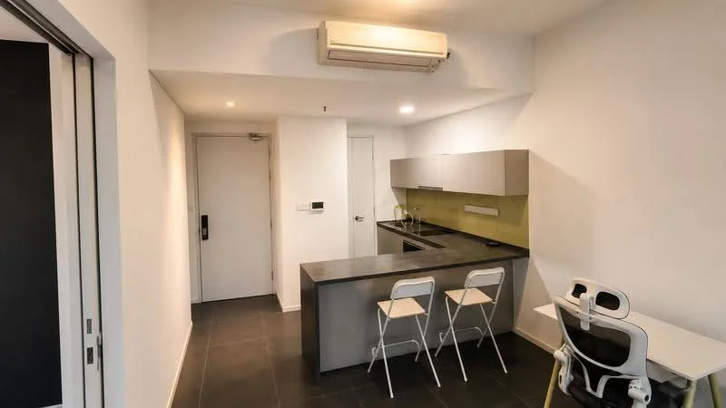 Kitchen features: grey countertop, stainless-steel sink, chrome pull-down faucet, flat-panel grey cabinets, green backsplash, built-in oven, stainless-steel range hood, 2 bar stools, wall-mounted split AC, black tiled flooring, white painted walls, open layout; style: modern.