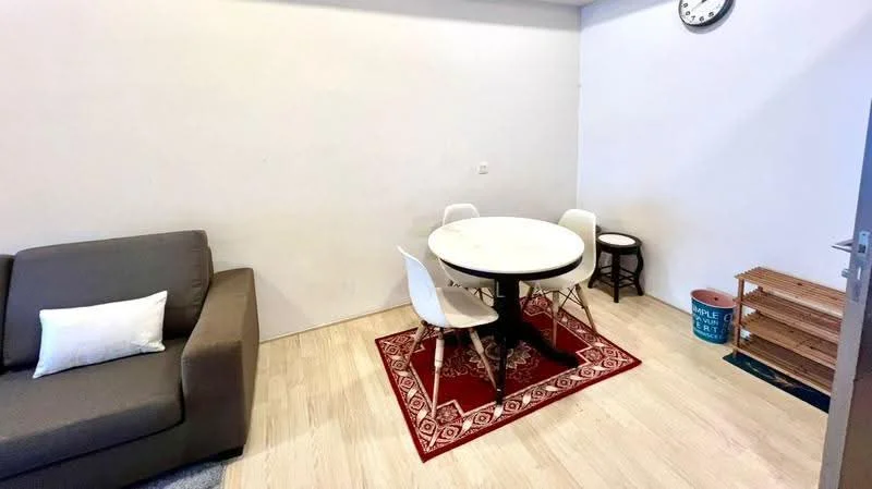 Dining features: round dining table, 4 white dining chairs, area rug with geometric pattern, grey fabric sofa, wall clock, wooden shelving unit, wooden stool, light wood flooring, plain white walls; style: modern.