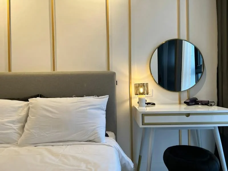 Bedroom features: king-size bed with upholstered headboard, white bedding, decorative pillows, nightstand with drawer, round mirror, table lamp, wall-mounted electrical outlet, gold accent wall paneling, curtains, window with view, black chair; style: modern.