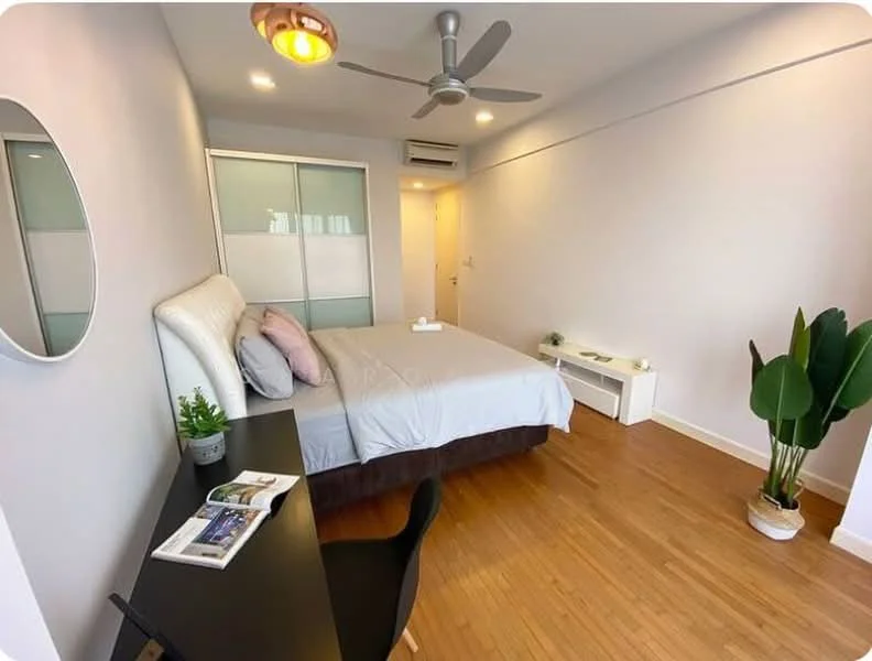 Bedroom features: queen-size bed with upholstered headboard, light grey bedding, wooden flooring, 5-blade ceiling fan, wall-mounted mirror, desk with black finish, black chair, decorative plant in pot, white bedside table, wall-mounted air conditioning unit, natural light from window, neutral painted walls; style: modern.