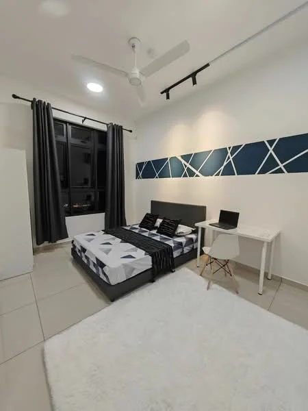 Bedroom features: queen-size bed with patterned bedding, upholstered headboard, 2 bedside pillows, white area rug, white desk with chair, black laptop on desk, ceiling fan, black curtains, floor-to-ceiling window, decorative wall with blue geometric pattern, light-colored tiled flooring, wall-mounted light fixture; style: modern.