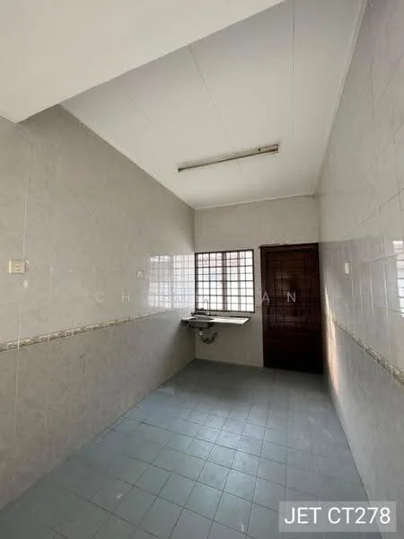 Room features: grey tiled flooring, light grey painted walls, white ceiling, single-bowl stainless-steel sink, window with metal grille, wall-mounted light fixture, decorative tile border, high ceiling.