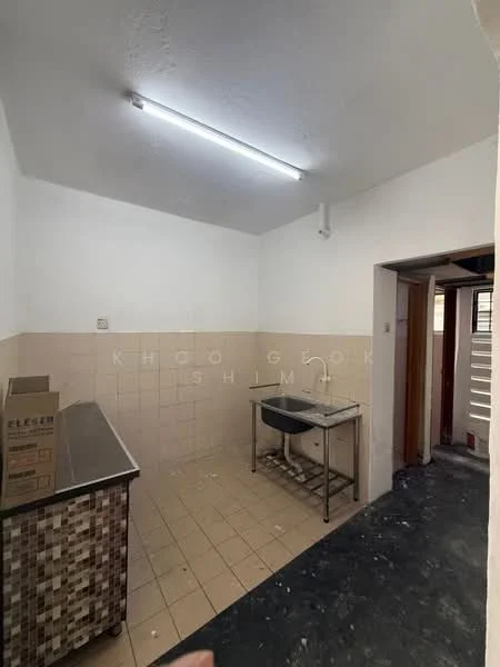 Kitchen features: white painted walls, cream tiled backsplash, grey tiled flooring, stainless-steel countertop, metal table, single-bowl sink, fluorescent ceiling lights, open layout.