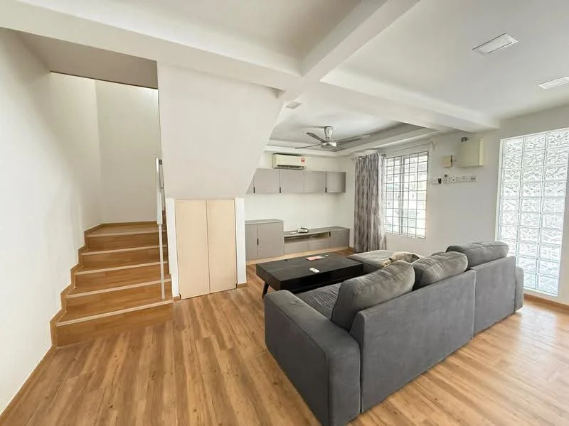 Living features: grey fabric sofa, coffee table, wooden flooring, ceiling fan, large windows, white painted walls, open layout, staircase leading to upper level, built-in cabinetry in kitchen area; style: modern.