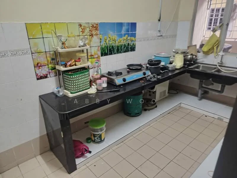Kitchen features: black countertop, white tiled walls, ceramic tile flooring, stainless-steel sink, chrome faucet, gas stove with multiple burners, kitchen cabinets, decorative wall tiles with floral pattern, plastic storage containers, kettle, blender, cooking utensils, open shelving, wall-mounted electrical outlets.
