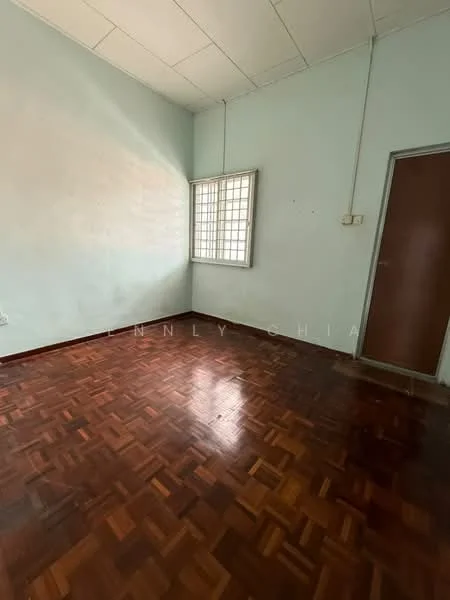 Room features: light blue painted walls, parquet wood flooring, single window with grid pattern, wooden door, high ceiling, no visible furniture, natural light from window, empty room.