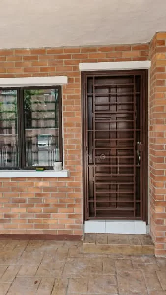Exterior features: red brick facade, brown metal security door with grid pattern, white window frame, black window with vertical bars, stone step at entrance, textured concrete flooring, paved walkway; style: modern.