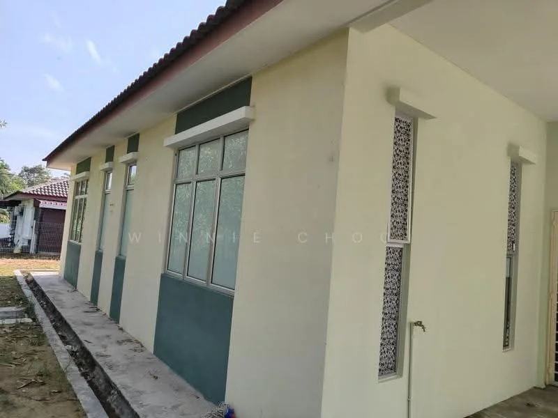Exterior features: white painted facade, green accent wall, large windows with decorative grills, concrete pathway, single-storey, gabled roof, surrounded by grass, side entrance door; style: modern.