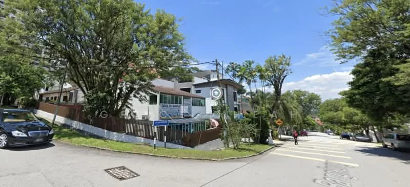 Exterior type: detached bungalow; features: white painted facade, two-storey building, surrounded by mature trees, manicured lawn, driveway with interlocking pavers, balcony on upper floor, fenced yard, street view with pedestrian crossing; style: modern.