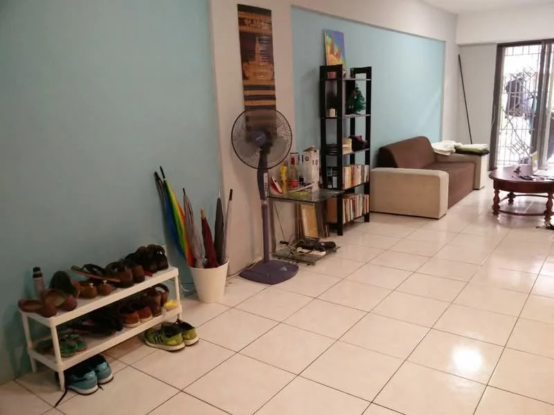 Living features: light blue painted walls, white tiled flooring, 3-seater fabric sofa in beige, wooden coffee table, bookshelf with books and decorative items, floor fan, shoe rack with shoes, umbrella stand with umbrellas, natural light from window, decorative artwork on wall; style: modern.