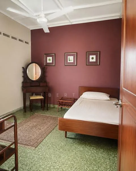 Bedroom features: green terrazzo flooring, brown wooden bed frame with mattress, wooden bedside table, wooden dressing table with mirror, 3 framed wall art pieces, ceiling fan, area rug, built-in wardrobe, white painted walls, accent wall in maroon; style: traditional.