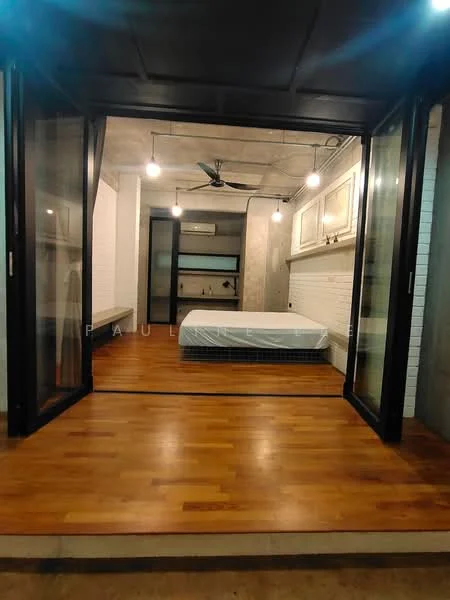 Bedroom features: wooden flooring, exposed concrete walls, black ceiling with pendant lights, 5-blade ceiling fan, floor-to-ceiling glass doors, white painted walls, built-in wardrobe, unmade bed with mattress; style: modern; view: garden.