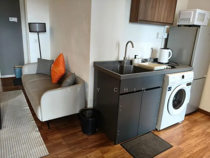 Room features: light wood flooring, white walls, grey cabinetry, stainless-steel sink, chrome pull-down faucet, built-in microwave, white washing machine, refrigerator, black waste basket, orange decorative pillow, sofa with fabric upholstery, black floor lamp, countertop with cutting board; style: modern.
