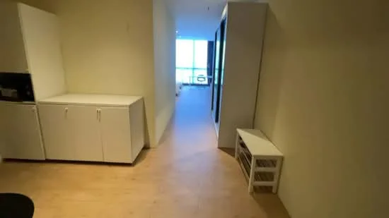 Room features: light wood flooring, white cabinetry, microwave, open space layout, large windows, neutral wall color, minimalist design, built-in storage, natural light; style: modern.
