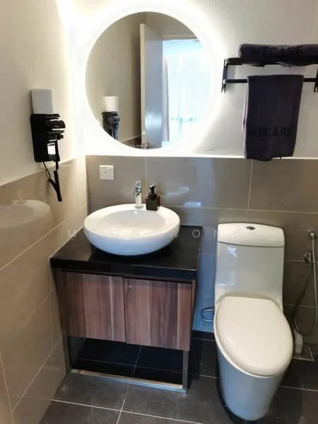 Bathroom features: round mirror with backlighting, wall-mounted soap dispenser, single-bowl ceramic sink, chrome basin mixer faucet, wooden vanity with black countertop, one-piece toilet, towel rack, grey tiled walls, dark grey tiled flooring; style: modern.