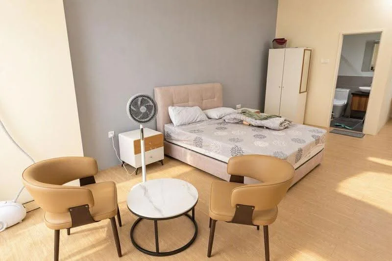 Bedroom features: queen-size bed, upholstered headboard, bedding with floral pattern, 2 beige armchairs, round marble-top coffee table, floor fan, light wood flooring, neutral painted walls, built-in wardrobe, window with natural light; style: modern.