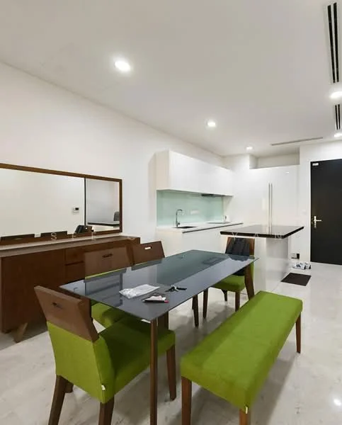 Dining features: rectangular dining table with black glass top, 4 green upholstered dining chairs, wooden bench seating, mirror on wall, white cabinetry with upper and lower storage, kitchen area with white cabinets, green backsplash, stainless-steel sink, built-in kitchen appliances, marble flooring, recessed ceiling lights; style: modern.