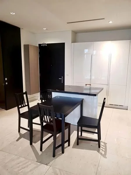 Kitchen features: white cabinetry, black countertop, four black dining chairs, built-in refrigerator, marble tile flooring, recessed downlights, dark wood accent wall, open layout; style: modern.