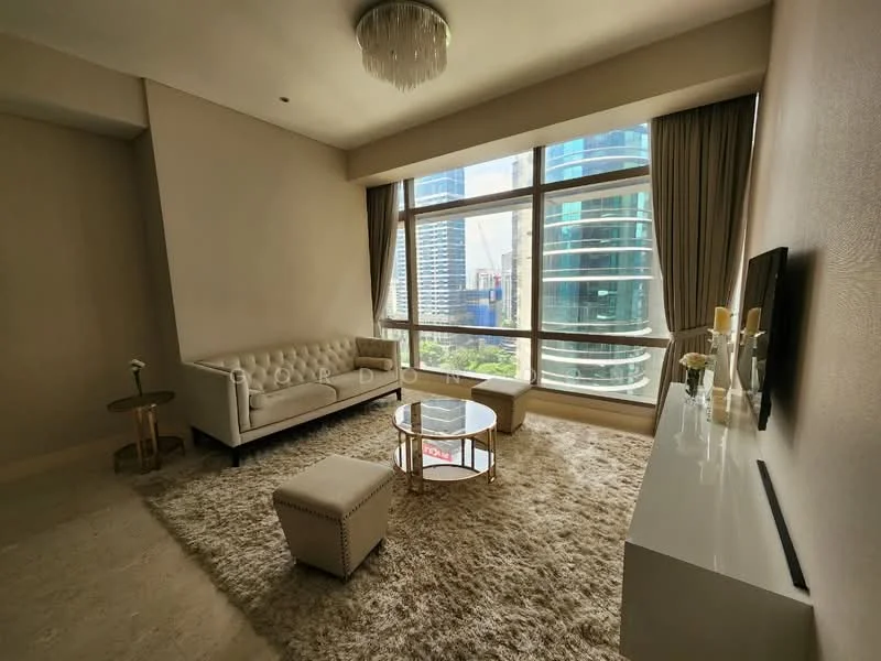 Living features: beige tufted fabric sofa, round glass coffee table, white TV console, large floor-to-ceiling windows, city skyline view, cream area rug, chandelier, curtains, decorative vase, wall-mounted TV; style: modern; view: city.