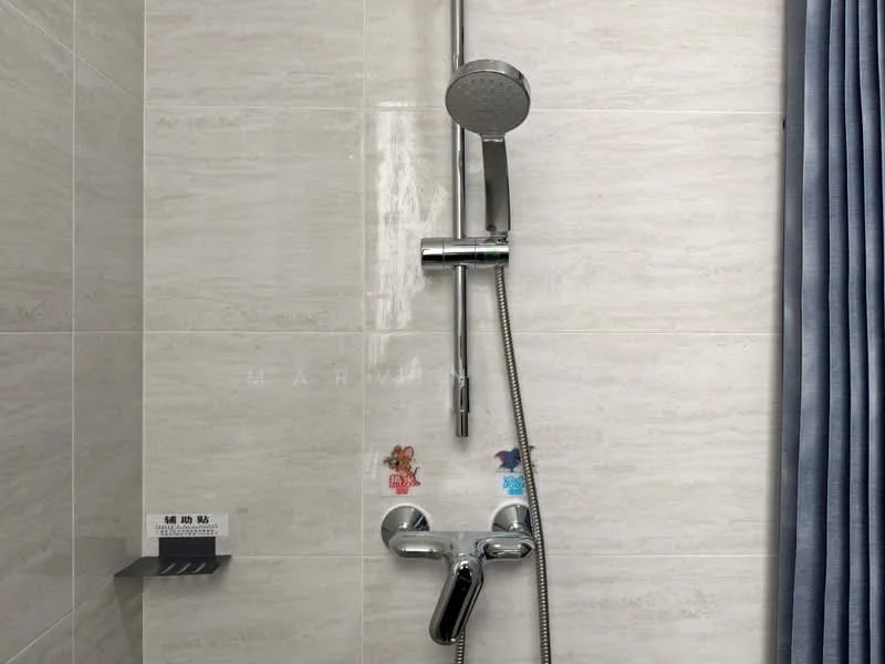 Bathroom features: chrome shower head, chrome handheld shower, chrome shower valve, grey tile walls, light grey tile flooring, shower caddy, curtain for privacy, decorative stickers on wall; style: modern.