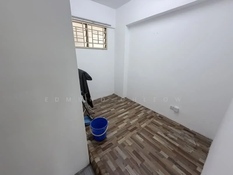 Room features: white painted walls, wooden flooring, window with metal grille, bucket, coat hanging, light switch.