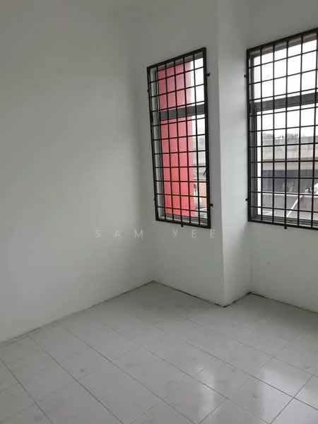 Room features: white painted walls, white tiled flooring, two large windows with security grills, natural light from windows, corner room layout.