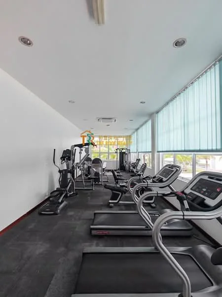 Room features: exercise equipment, treadmills, elliptical machine, stationary bike, large windows, blue blinds, grey carpet flooring, ceiling lights, wall-mounted air conditioning unit; style: modern; view: garden.