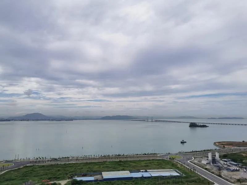 Exterior features: waterfront view, city skyline in background, bridge visible, island in water, cloudy sky, landscape with greenery.
