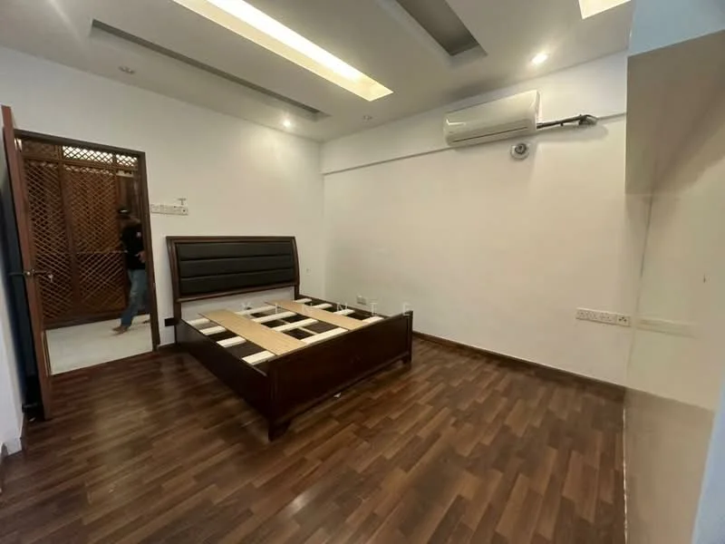 Bedroom features: wooden flooring, false ceiling with recessed lighting, wall-mounted air conditioning unit, brown wooden bed frame without mattress, white painted walls, built-in wardrobe with wooden slats, single window, no visible decor; style: modern.