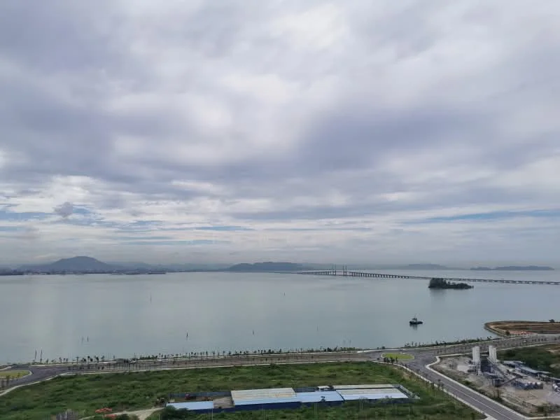 Exterior features: waterfront view, city skyline in background, bridge visible, island in water, cloudy sky, green landscape in foreground.