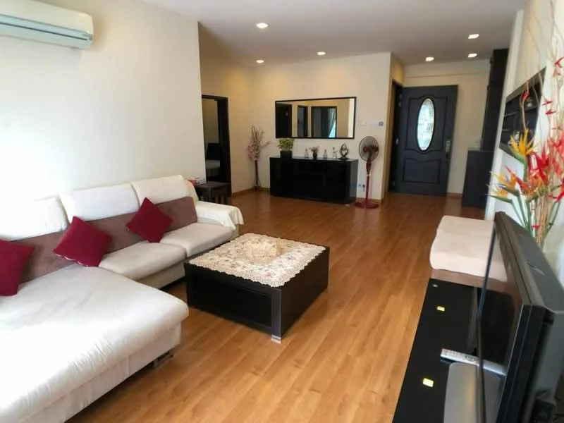 Living features: L-shape sectional sofa in cream and brown, red accent cushions, coffee table with black surface, wooden flooring, wall-mounted TV, TV console, decorative wall mirror, air conditioning unit, recessed ceiling lights, fan, decorative plant, neutral painted walls, entrance door with glass panel; style: modern.