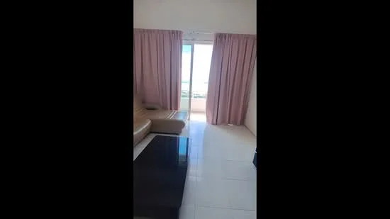 Living features: floor-to-ceiling windows, sliding glass door, pink curtains, cream walls, white tiled flooring, sofa, coffee table, ocean view; style: modern; view: sea.