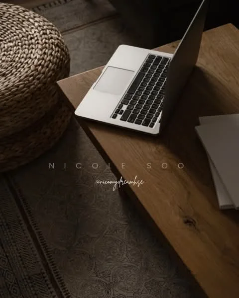 Room features: wooden coffee table, laptop on table, stack of papers, woven storage basket, textured area rug; style: modern.