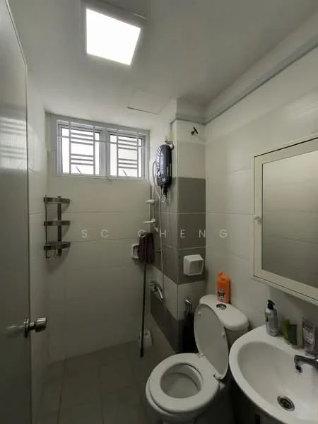 Bathroom features: white tiled walls, grey accent wall, ceramic tile flooring, single-sink vanity with mirror, one-piece toilet, shower area with glass partition, wall-mounted shower head, towel rack, soap dispenser, toilet paper holder, window with metal grille; style: modern.