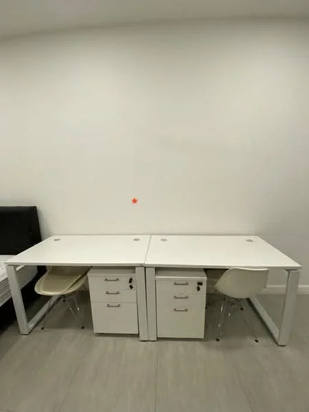 Room features: white walls, light grey flooring, two white desks, two white chairs, desk drawers, minimalist design; style: modern.