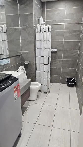 Bathroom features: grey tiled walls, light grey tiled flooring, white toilet, single-sink vanity with wood cabinet, mirror above vanity, shower with curtain, washing machine, towel rack, waste bin; style: modern.