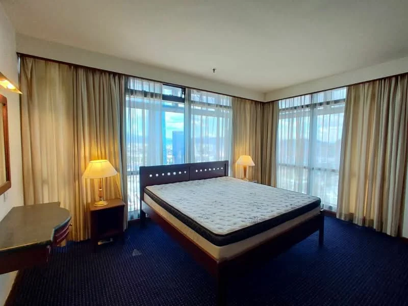 Bedroom features: king-size bed frame, mattress on bed frame, two bedside lamps, floor-to-ceiling windows, curtains, carpet flooring, wall-mounted mirror, wooden desk, wooden chair; style: modern; view: city.