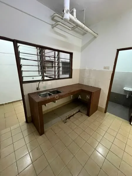 Kitchen features: single-bowl stainless-steel sink, brown laminate countertop, wall-mounted faucet, tile backsplash, cream tiled walls, beige floor tiles, window with metal grilles, open layout, exposed plumbing, built-in cabinetry, light fixture on ceiling. Room features: toilet visible in adjacent room, cream tiled walls, beige floor tiles.