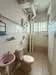 Bathroom features: white tiled walls, cream tiled flooring, one-piece toilet, chrome basin mixer faucet, framed mirror, shower area with glass partition, handheld shower, wall-mounted towel rack, window for natural light; style: modern.