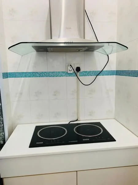 Kitchen features: induction cooktop, stainless-steel range hood, white countertop, white cabinetry, blue mosaic tile backsplash, white tiled walls, electrical outlet; style: modern.