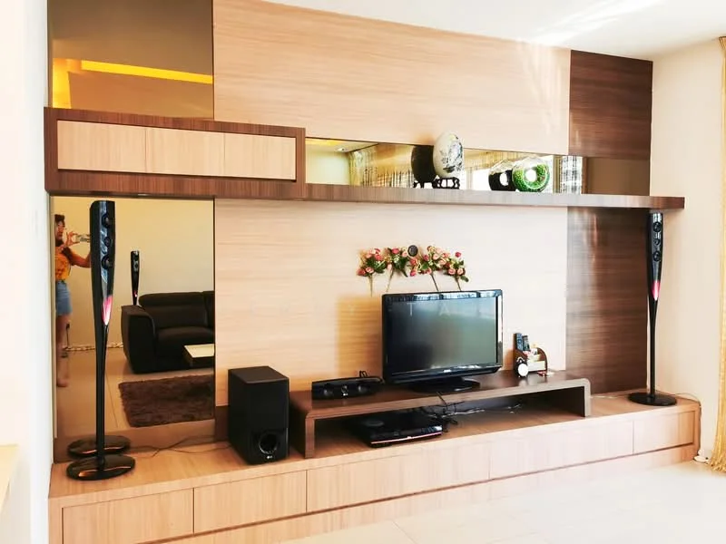 Living features: wood panel feature wall, built-in shelving, flat-screen TV, black speaker system, decorative flower arrangement, mirrored sections, light-colored flooring, sofa in background; style: modern.