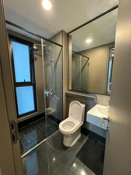 Bathroom features: glass shower enclosure, rain shower head, handheld shower, white toilet, single-sink vanity with white cabinet, mirror above sink, grey tiled walls, black tiled flooring, recessed lighting, window for natural light; style: modern.