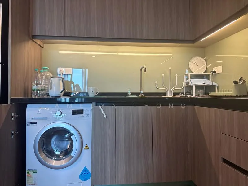 Laundry features: built-in cabinetry with wood finish, black countertop, single-bowl stainless-steel sink, chrome pull-down faucet, front-load washing machine, glass backsplash, under-cabinet lighting, bottled water, kettle, white ceramic cup; style: modern.