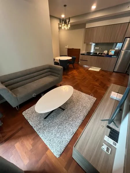 Living features: grey fabric 3-seater sofa, round coffee table with white top, area rug with geometric pattern, wooden TV console, wall-mounted TV, chandelier with multiple bulbs, wooden flooring, open-plan layout to kitchen and dining area; style: modern. Kitchen features: wood cabinetry, stainless-steel fridge, built-in oven, countertop with sink, kitchen island, ceramic tile backsplash; style: modern. Dining features: round dining table, 4 dining chairs; style: modern.