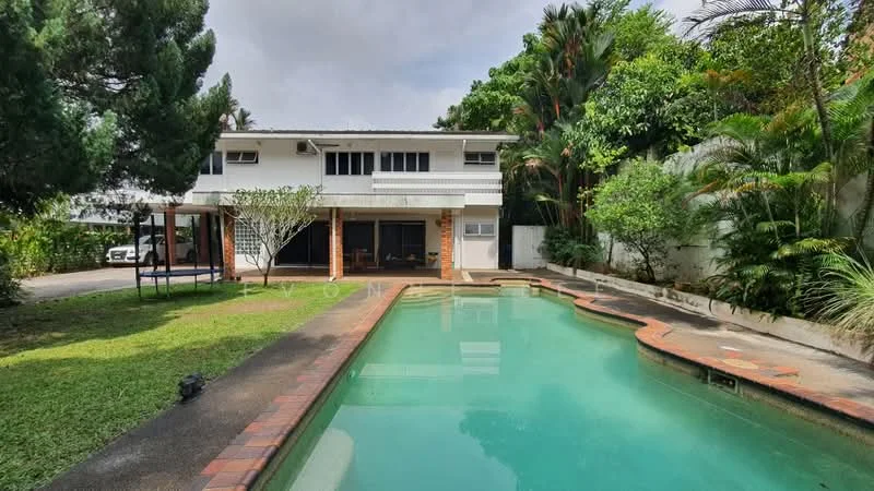 Exterior type: detached bungalow; features: swimming pool with curved edge, manicured lawn, tropical landscaping with palm trees, two-storey building, white painted facade, large windows, car parking area, patio area with outdoor seating, surrounded by greenery; style: modern.