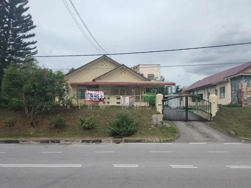 Exterior type: detached bungalow; features: cream painted facade, pitched tile roof, manicured lawn, mature trees, gated entrance, driveway with interlocking pavers, front porch with overhang, decorative stone cladding, surrounded by greenery; style: traditional.