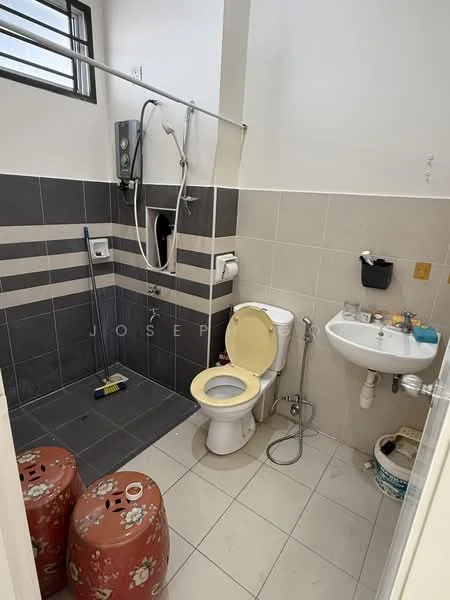 Bathroom features: white toilet, single-sink vanity with wall-mounted faucet, shower area with wall-mounted shower head, grey tiled walls, cream tiled walls, floor tiles in light grey, toilet paper holder, handheld shower, two decorative stools, window for natural light; style: modern.