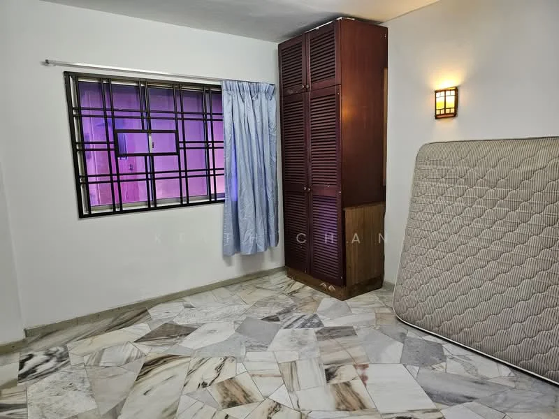 Room features: marble flooring, white painted walls, window with grid pattern, blue curtains, wooden wardrobe with louvered doors, wall-mounted light fixture, mattress leaning against the wall.