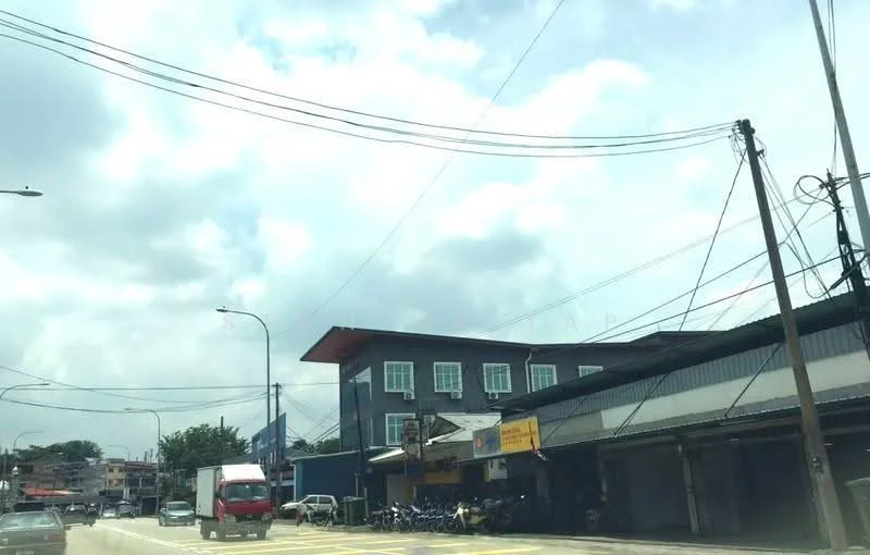 Exterior type: shophouse; features: two-storey building, blue painted facade, flat roof, large windows on upper floor, signage visible on ground floor, parking area in front, street view, surrounded by power lines, adjacent to road, motorcycles parked outside; style: modern.