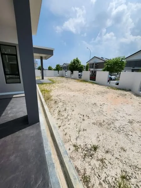 Exterior features: bare land, concrete boundary wall, landscaping with small trees, paved walkway, open space, surrounding residential area, clear sky; style: modern.